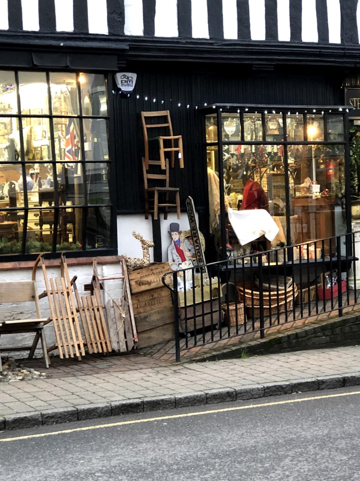 shop front with items on the pavement and lights over the windows